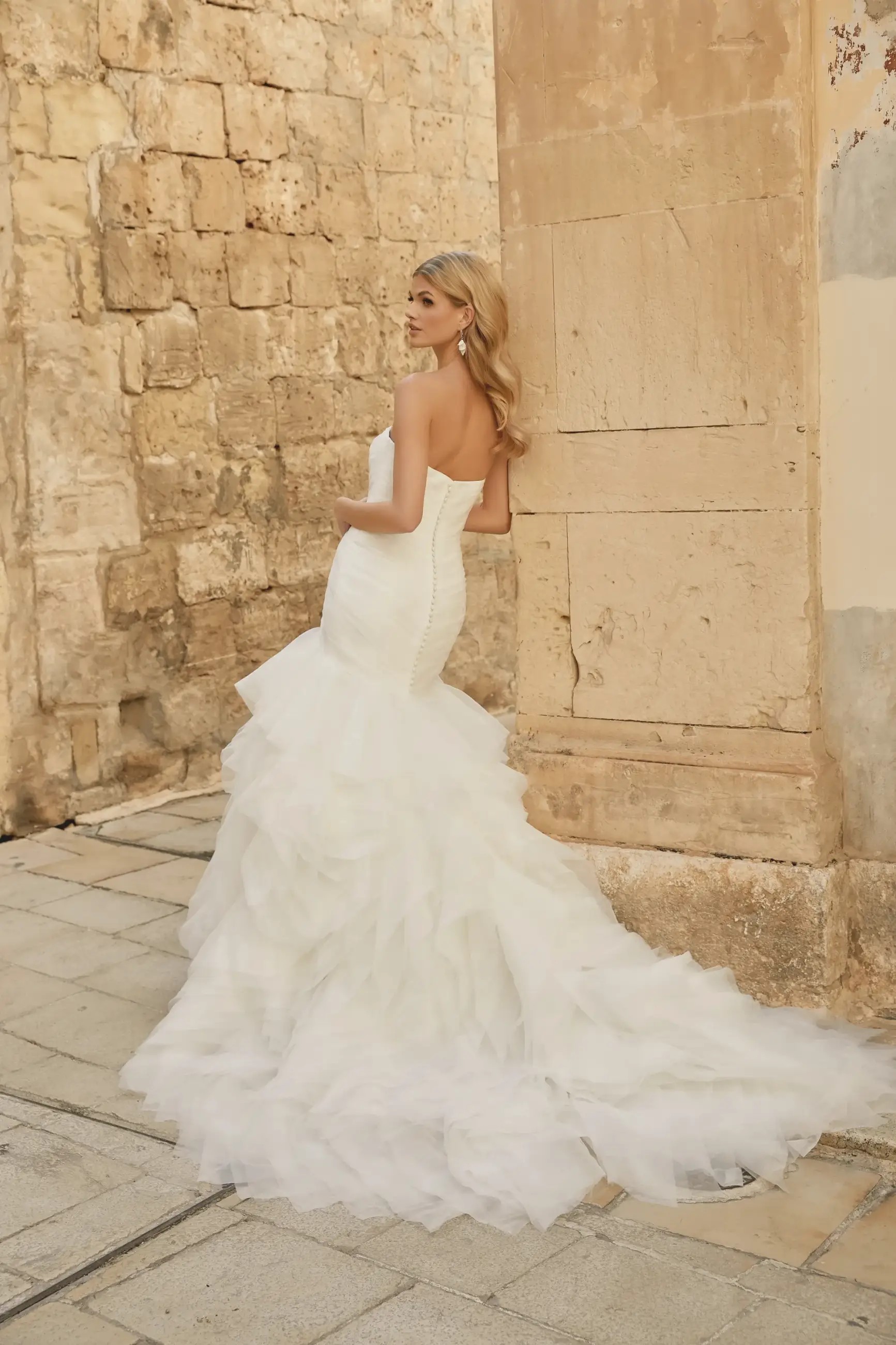 Model is wearing a strapless organza wedding dress by justin alexander sincerity