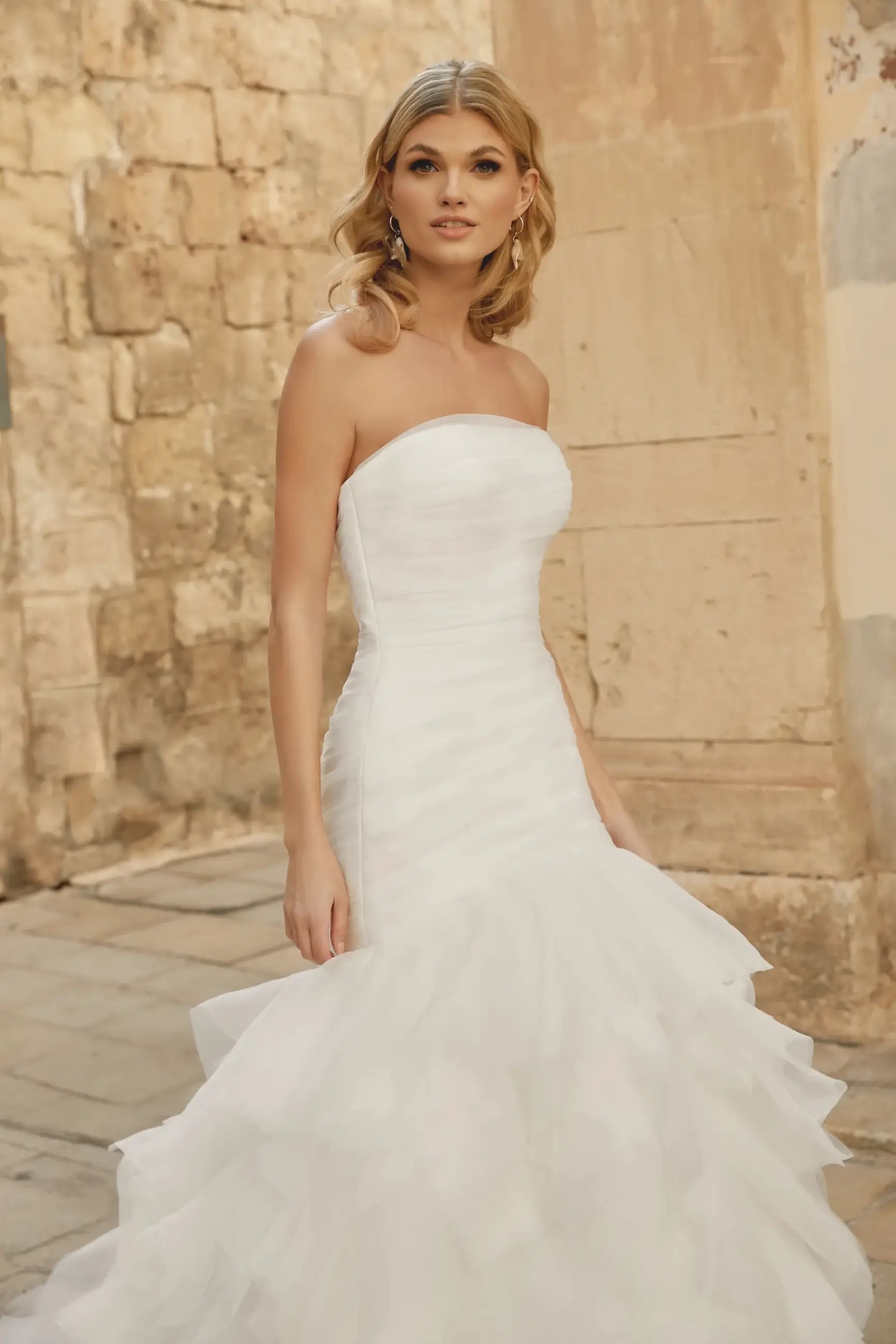 Model is wearing a strapless organza wedding dress by justin alexander sincerity
